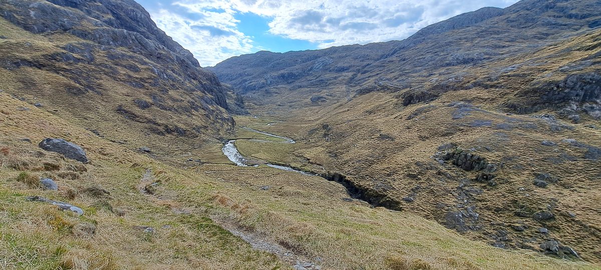 A green Highland glen with a stream on the Cape Wrath Trail