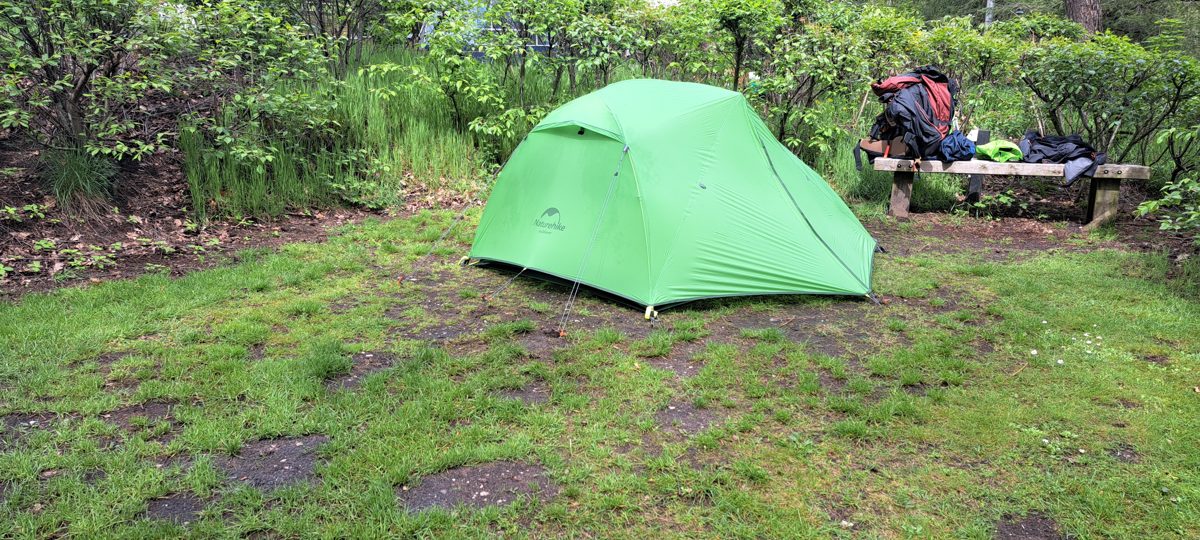 A green Naturehike Star River 2 tent pitched on the Veluwe with gear laid out