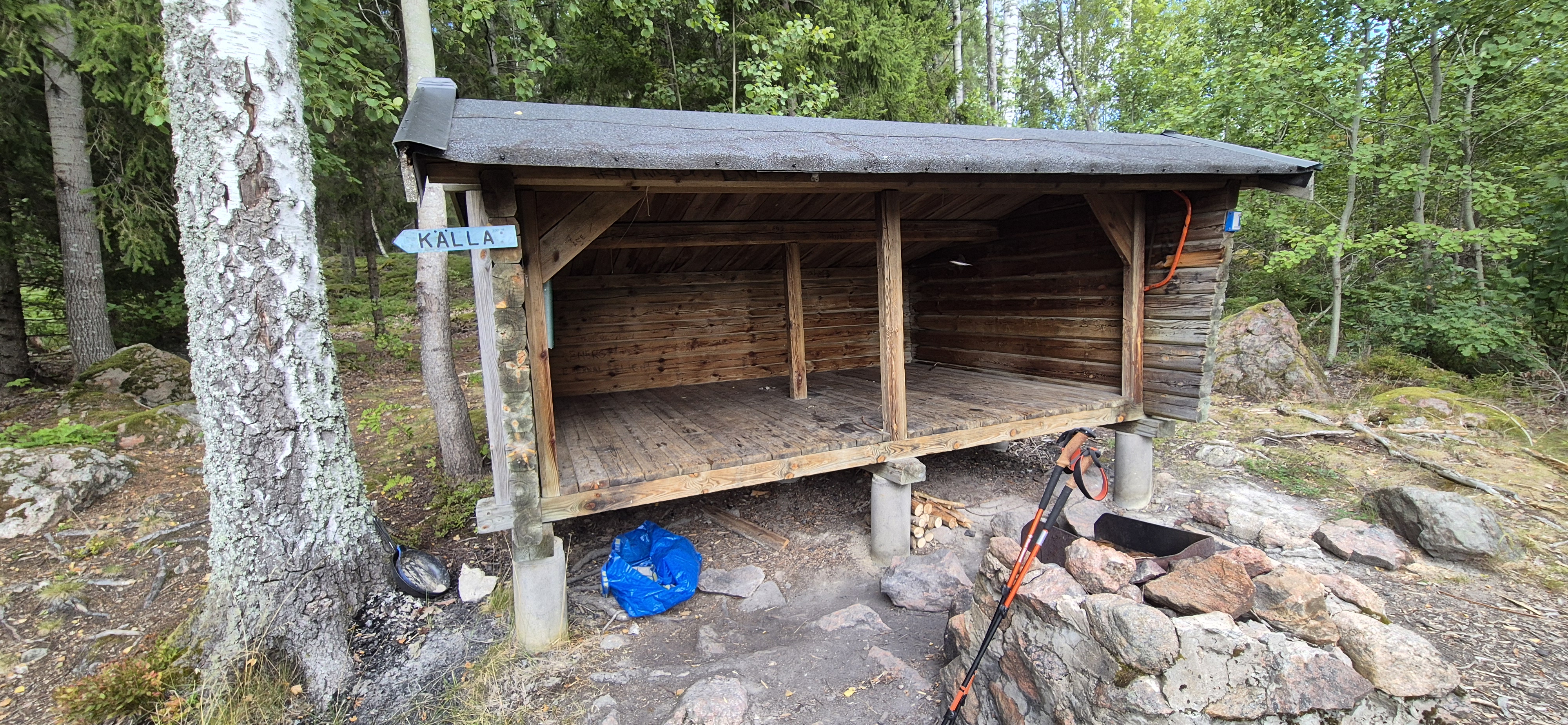 Open-sided Kalla log shelter on the Sörmlandsleden with hiking poles