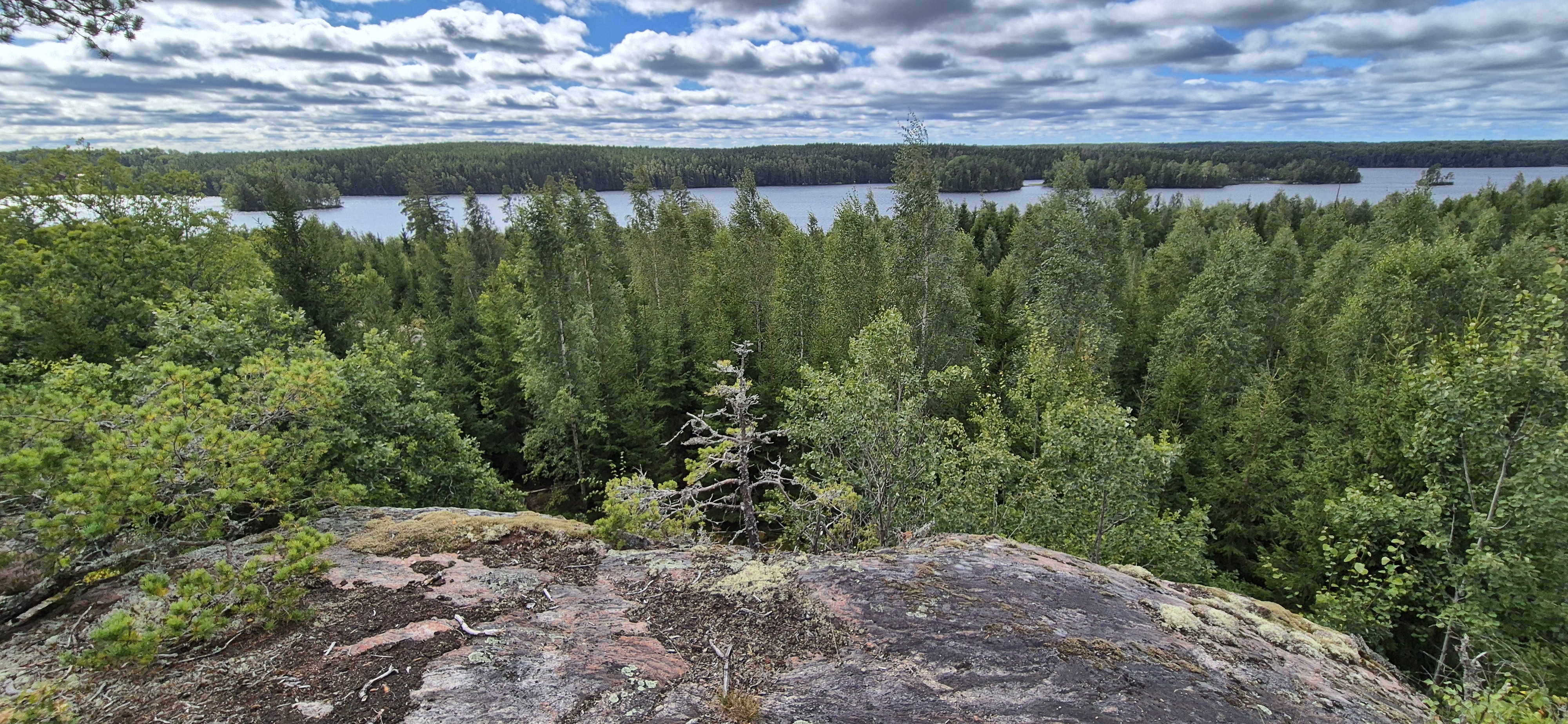 View from a granite rock outcrop over vast forest and a lake below