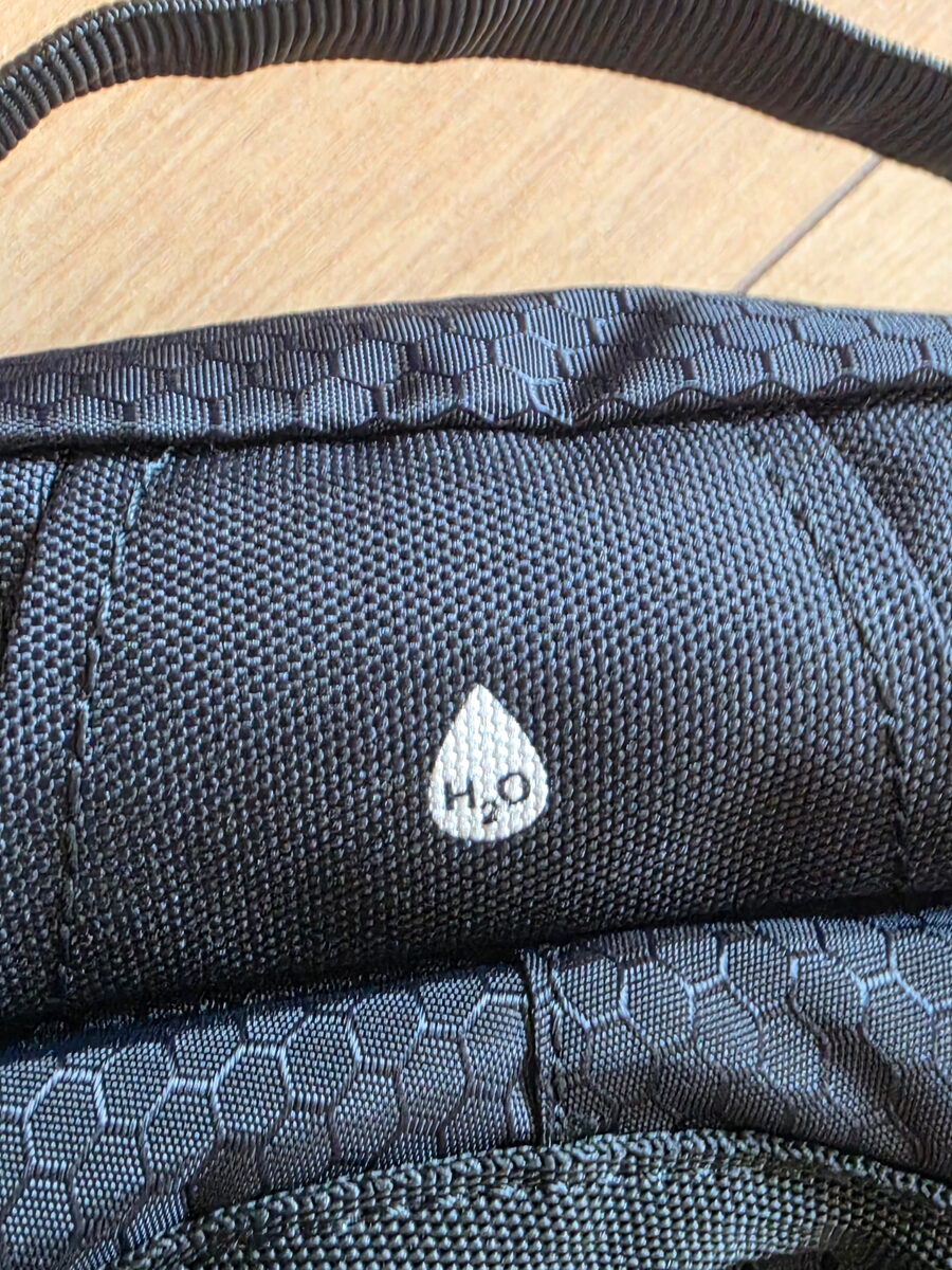 Hydration hose port marked with an H2O drop at the top of the back panel
